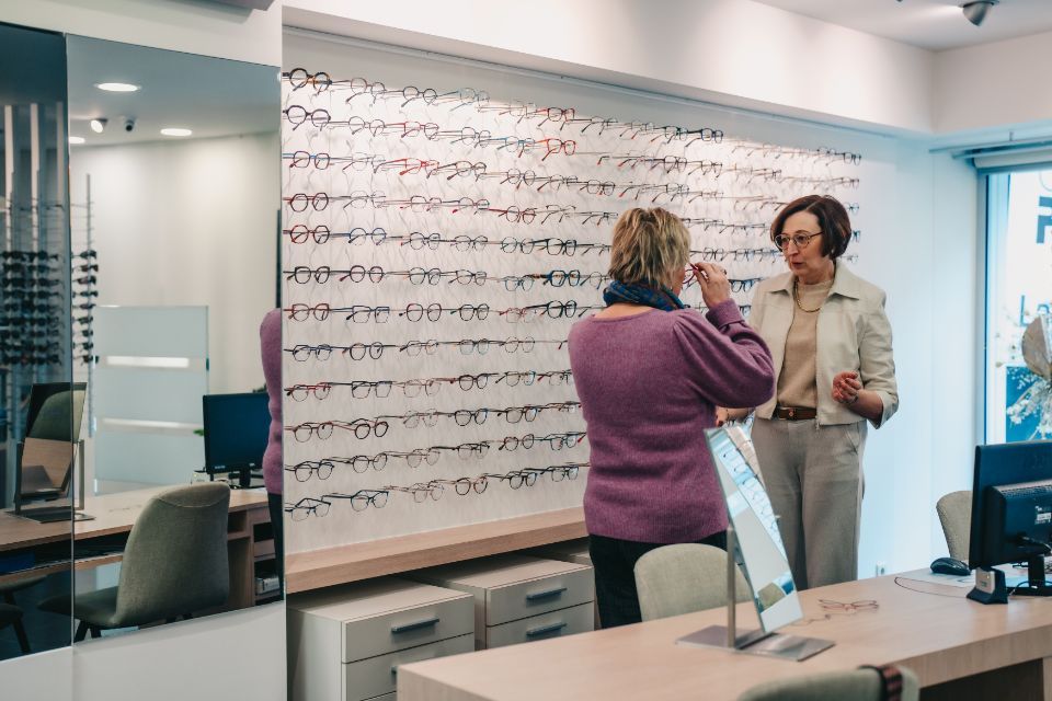 Marieke helpt klant met passen van bril bij grote keuze aan brillen